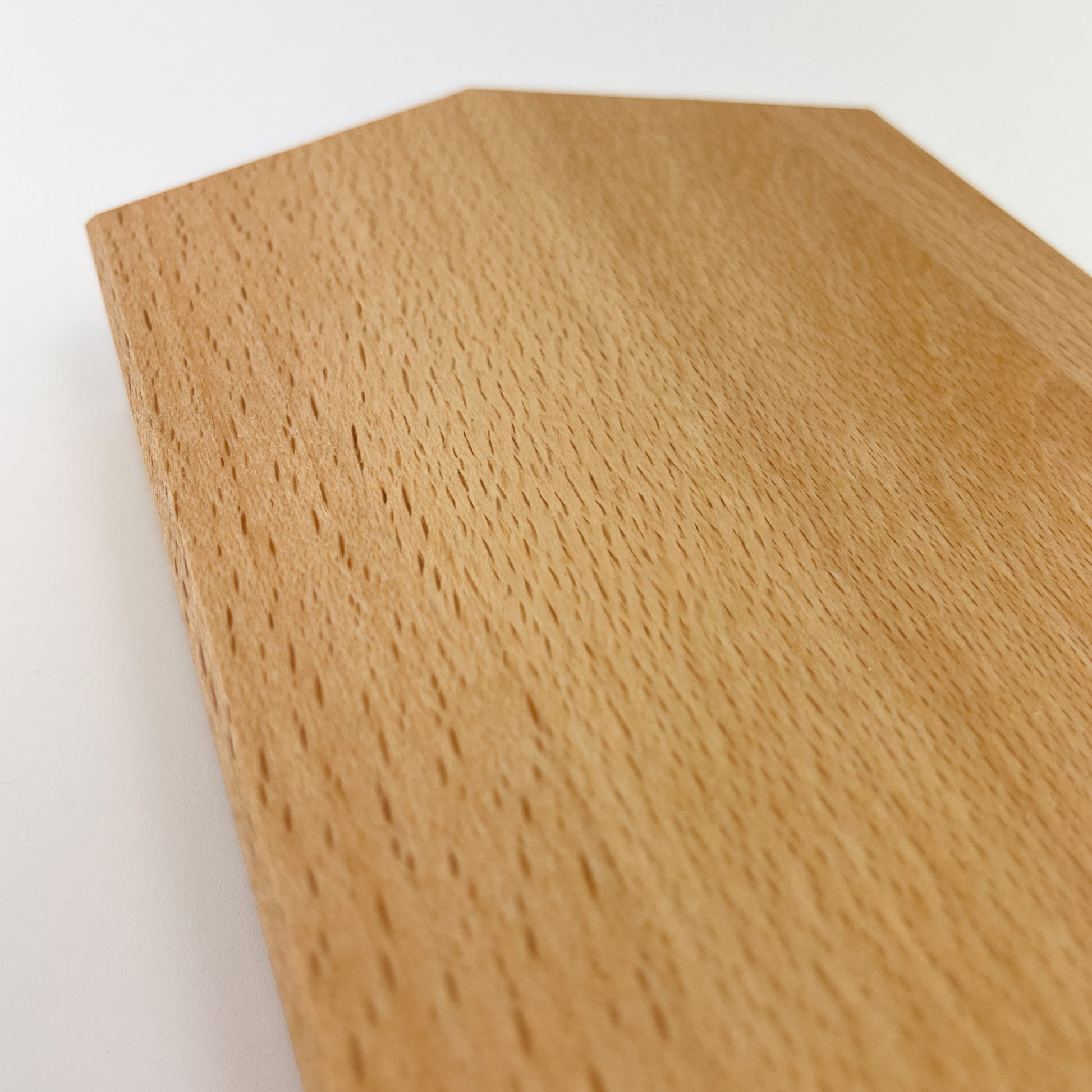 Detailaufnahme des Deko-Hauses aus massivem Buchenholz vor weißem Hintergrund. Zu sehen ist der Dachbereich des Hauses und die gefaste Kante sowie die Maserung des Holzes.