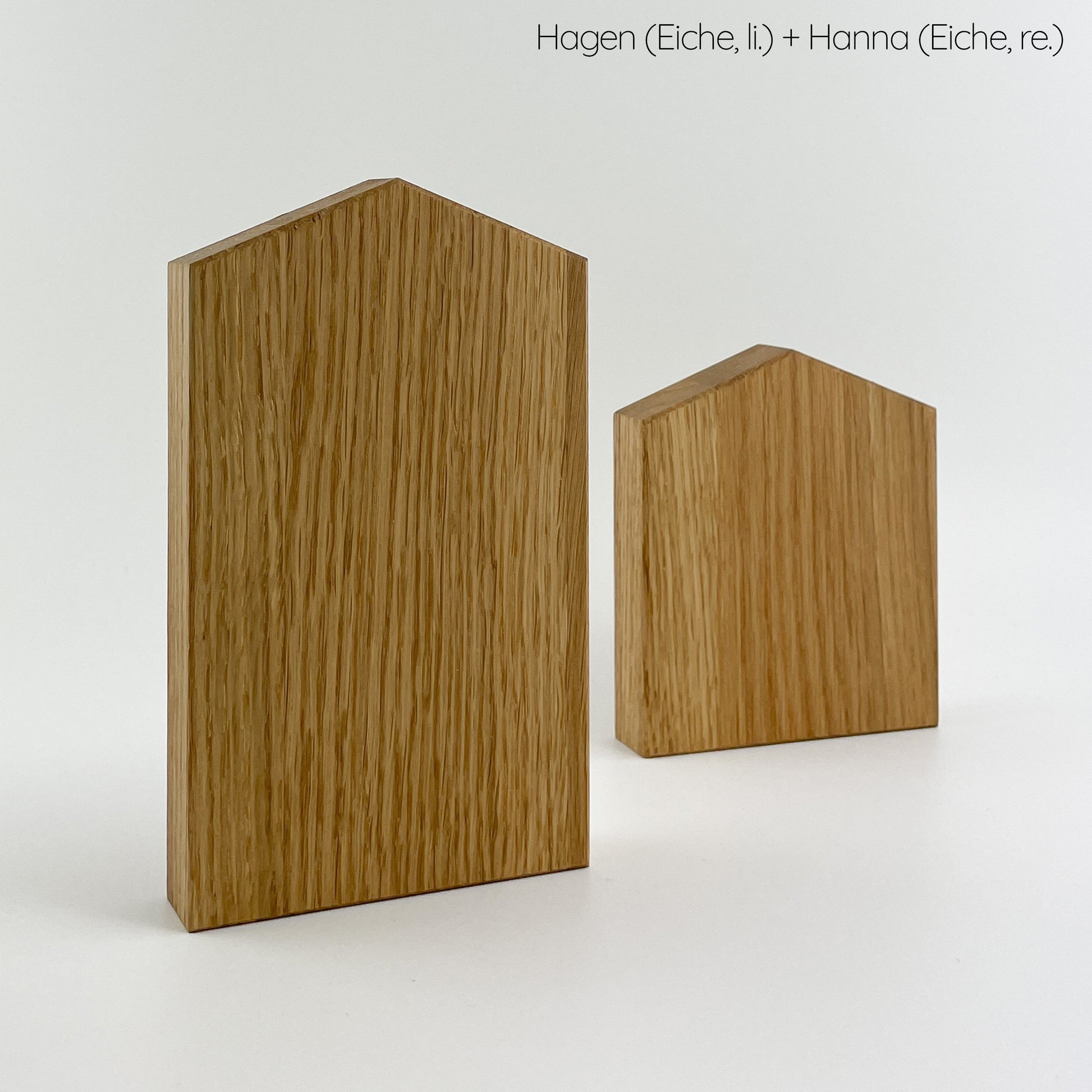 Zwei Deko-Häuser aus (Eichen-) Holz vor weißem Hintergrund. Das größere steht links und etwas weiter im Vordergrund, das kleinere ist fast quadratisch und steht rechts etwas weiter hinten. Die Maserung des Holzes verläuft vertikal und ist gut erkennbar.