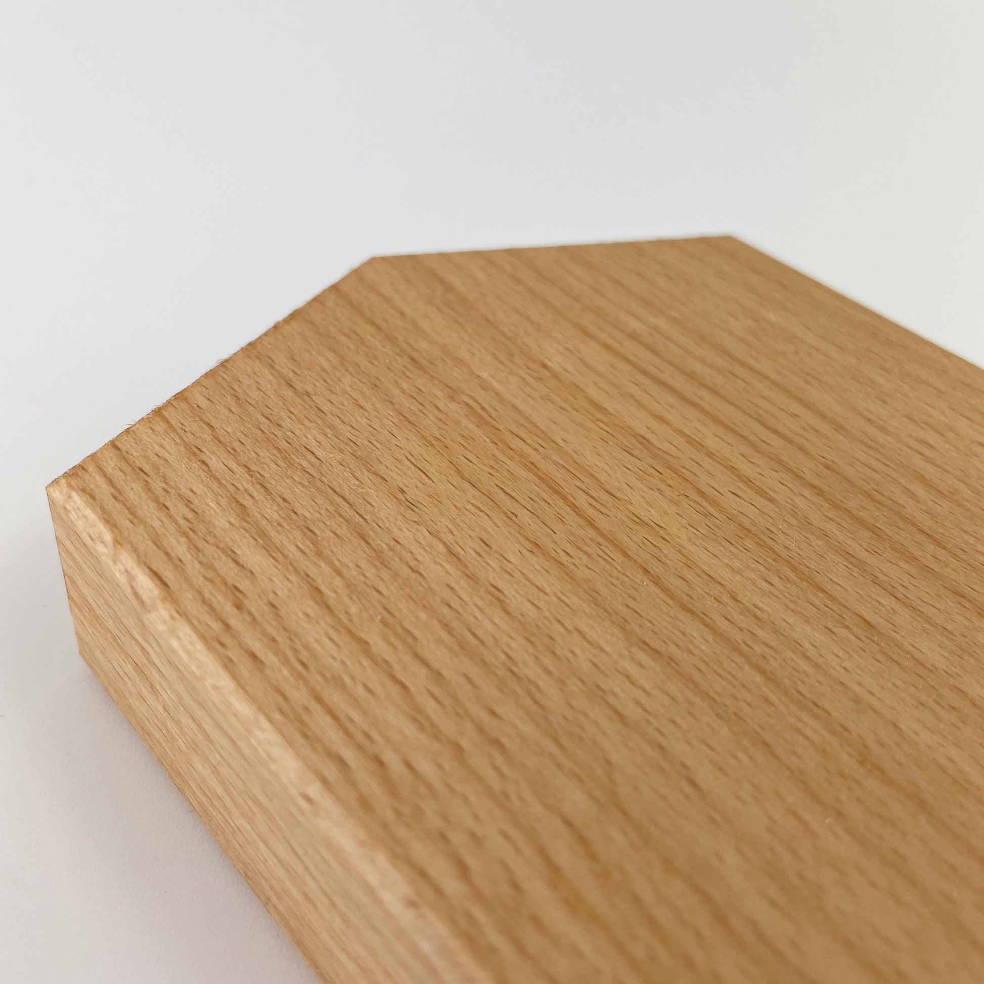 Detailaufnahme des Deko-Hauses aus massivem Buchenholz vor weißem Hintergrund. Zu sehen ist der Dachbereich des Hauses und die gefaste Kante sowie die Maserung des Holzes.