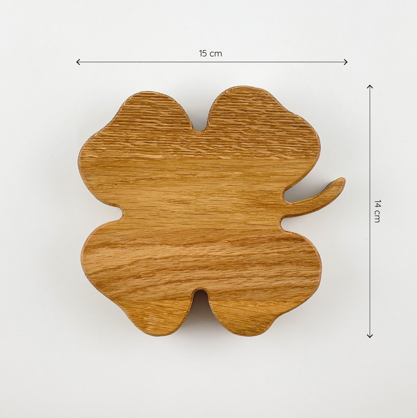 Das Deko-Kleeblatt aus Massivholz (Eiche) von oben gesehen auf einem weißen Untergrund. Oberhalb und rechts sind zwei Maßketten zu sehen, welche die Dimensionen des Kleeblattes angeben - es ist 15cm breit und 14cm hoch.