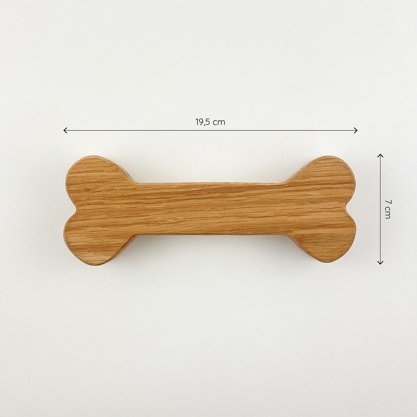 Der dekorative Knochen aus Holz von oben gesehen vor weißem Hintergrund. Darüber und rechts daneben sind zwei Maßketten zu sehen, welche die Größe des Knochens definieren - er ist 19,5cm lang und 7cm hoch.
