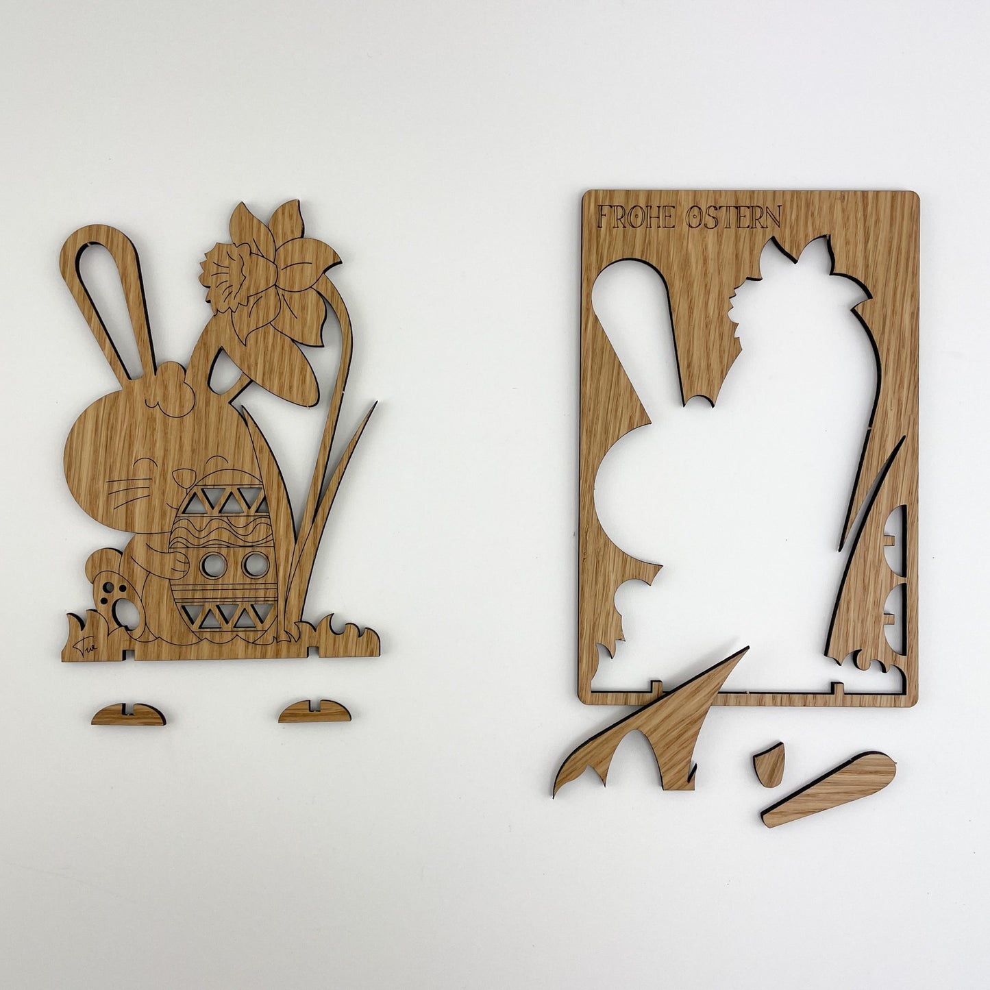 Frontalansicht von Holz-Osterkarten Pascal zeigt den Ausschnitt von Holz-Osterkarte Pascal. Die rechte Karte hat die Silhouette eines Hasen, über dem die Worte “FROHE OSTERN” stehen. Beide Karten sind aus Holz gefertigt und weisen filigrane Details auf, die ihre handwerkliche Qualität und das festliche Design betonen.