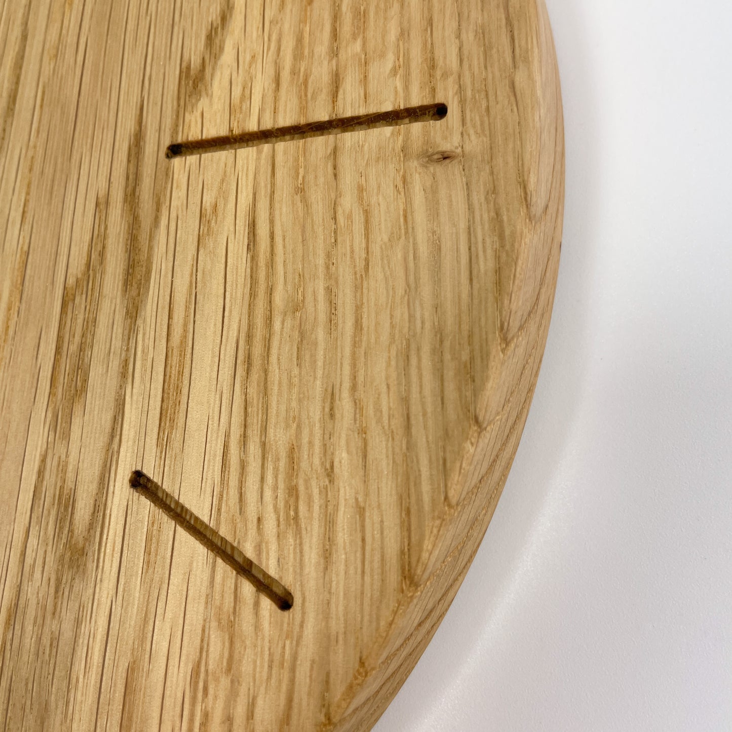 Detailansicht des Rands einer runden Holz-Wanduhr bei der die Stunden durch Striche gekennzeichnet sind.