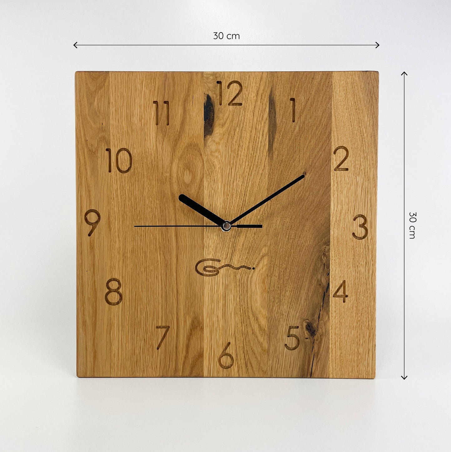 Frontalansicht einer eckigen Holz-Wanduhr mit schwarzen Zeigern, bei der die Zahlen die die Stunden anzeigen eingraviert sind Maße von 30x30 cm sind an der rechten und oberen Seite abgebildet.