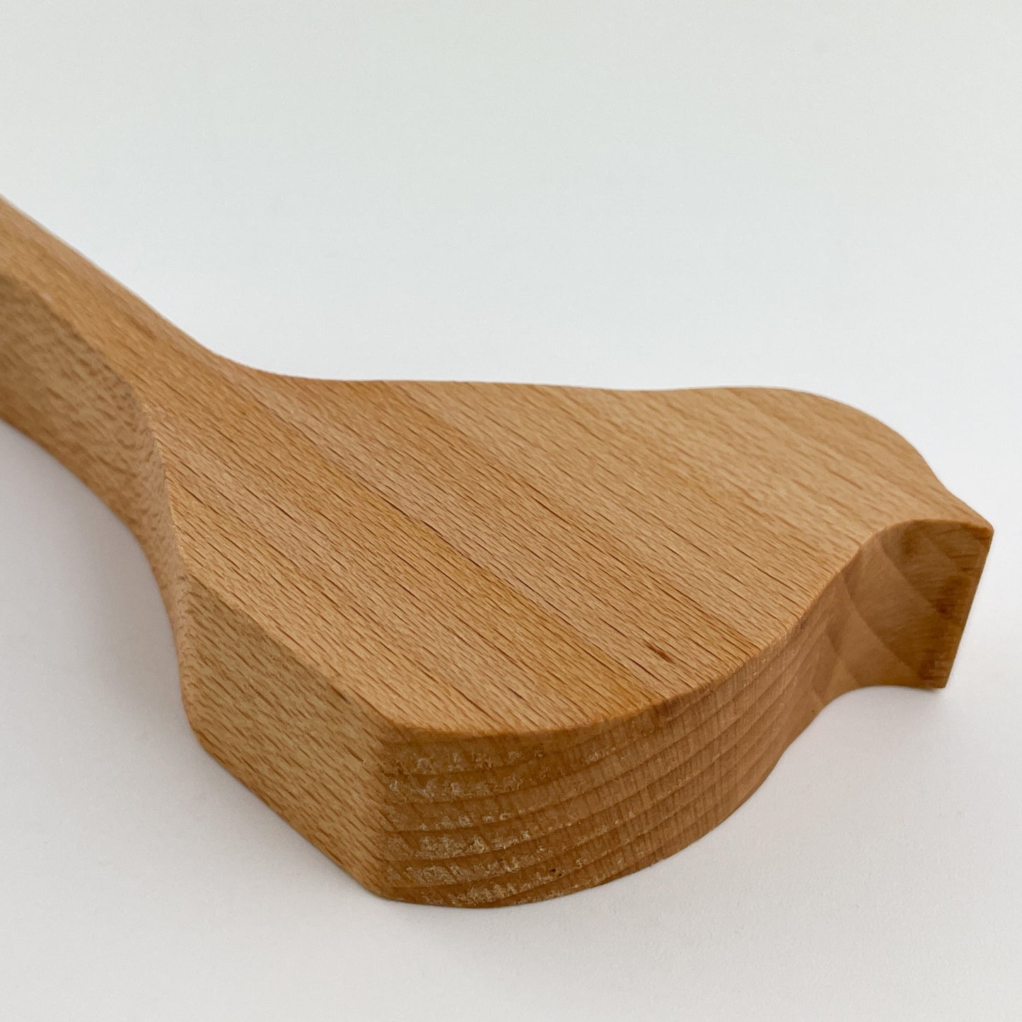 Detailansicht von Holzvogel Kiki, aus Holz, präzise gefertigt mit sichtbaren Holzmaserungen und einer glatten Oberfläche. Das Bild zeigt einen hölzernen Gegenstand mit einer Form, die an einen Vogel erinnert, wobei der Fokus auf dem detaillierten Schnitt und der natürlichen Textur des Materials liegt.