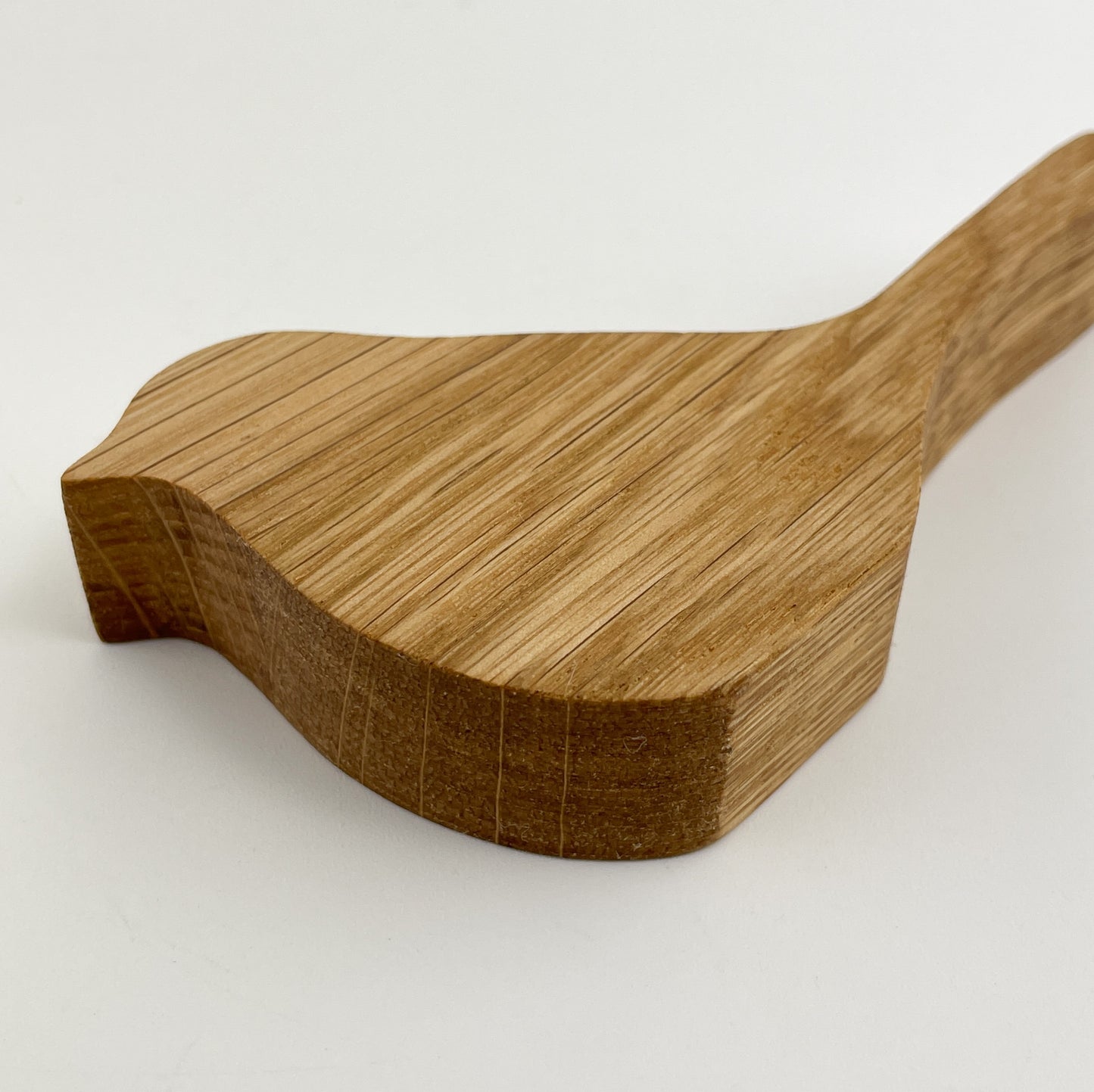 Detailansicht von Holzvogel Kiki, aus Holzmaterial, präzise gefertigt mit sichtbaren Holzmaserungen und einer glatten Oberfläche. Das Bild zeigt einen hölzernen Gegenstand mit einer Form, die an einen Vogel erinnert, wobei der Fokus auf dem detaillierten Schnitt und der natürlichen Textur des Materials liegt.