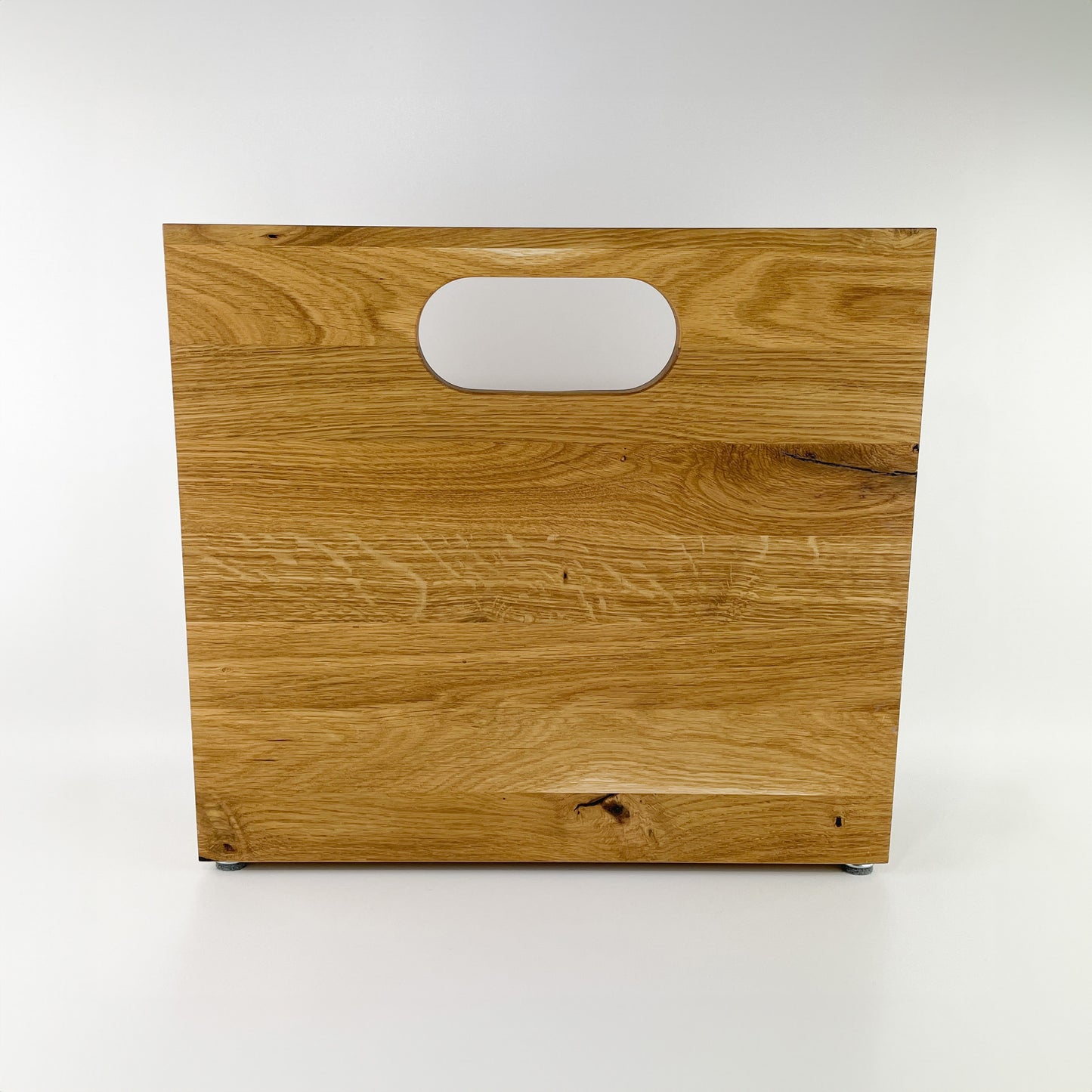 Rückansicht eines Zeitungsständers aus Holz mit Handgriff an der hinteren, längeren Begrenzung des Stauraums. Deutlich erkennbare Maserung des hellen Holzes.