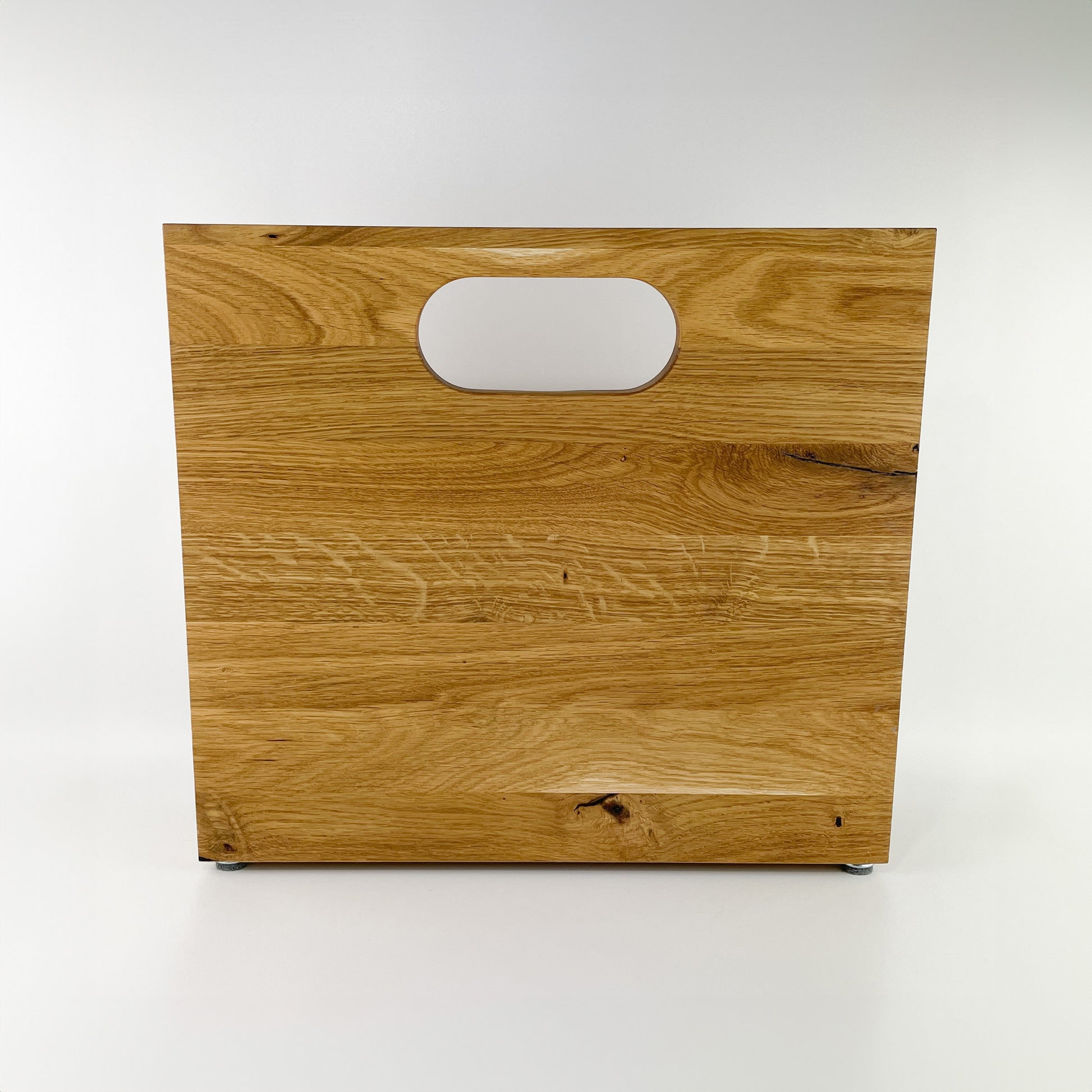 Rückansicht eines Zeitungsständers aus Holz mit Handgriff an der hinteren, längeren Begrenzung des Stauraums. Deutlich erkennbare Maserung des hellen Holzes.