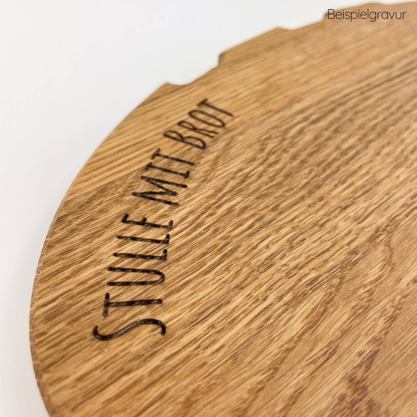 Detailansicht von Holz Schneidebrett - Bernd aus hellbraunem Holz mit individueller Gravur ‘Stulle mit Brot’ in geschwungener Schrift. Die Maserung des Holzes ist deutlich sichtbar und verleiht dem Schneidebrett eine natürliche und rustikale Ästhetik.