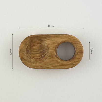 Der längliche Eierbecher aus Massivholz (Eiche) von oben gesehen. Links befindet sich die Vertiefung für die Eierschalen und rechts das Loch, um ein Ei hineinzustellen. Zu sehen sind außerdem drei Maßketten, welche die Größe des Eierbechers definieren - er ist 12cm lang und 6.5cm breit, das Loch für das Ei hat einen Durchmesser von 3.5cm.