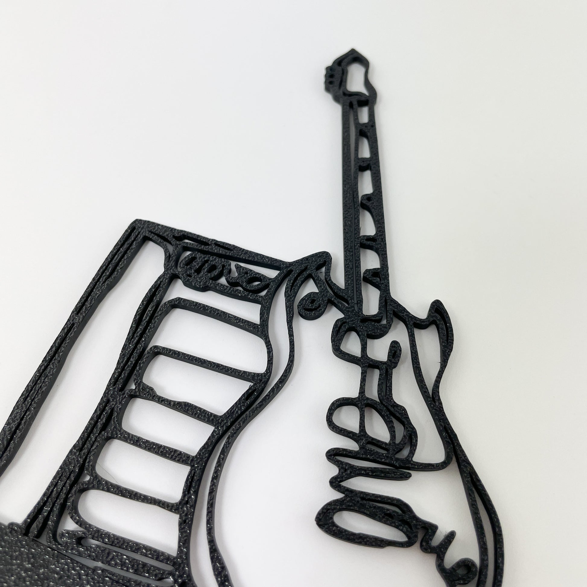 Detailaufnahme der 3D-gedruckten E-Gitarre mit Verstärker im Stil einer filigranen Linienzeichnung. Die Oberflächenstruktur des Kunststoffs ist gut zu sehen und der Hintergrund weiß.