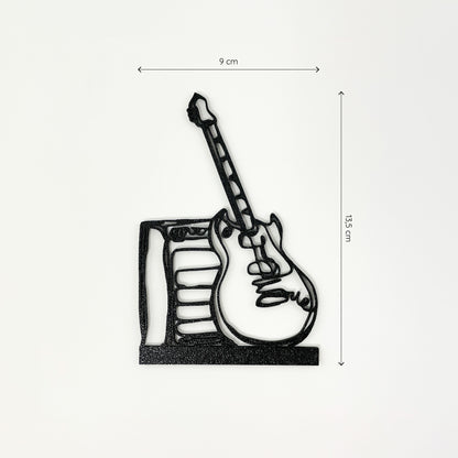 Frontalaufnahme des Steckbildes einer E-Gitarre mit Verstärker im Stil einer Linienzeichnung. Der Hintergrund ist weiß und oberhalb sowie rechts neben dem Motiv sind Maßketten eingezeichnet, welche die Größe definieren - es ist 9cm breit und 13,5cm hoch. Unten befindet sich ein breiterer Streifen, mit dem die E-Gitarre mit Verstärker in einen Halter gesteckt werden kann.