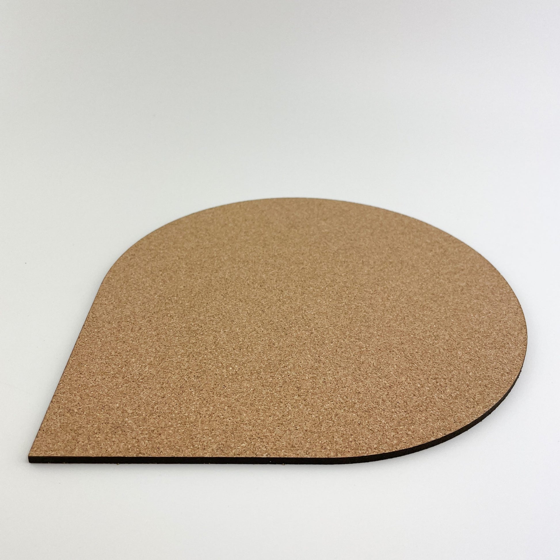 Detailansicht von ein halbrundes Mousepad aus Kork material auf einem weißen Hintergrund. Das Mousepad hat eine natürliche braune Farbe und eine glatte Oberfläche, die für eine angenehme Nutzung sorgt.