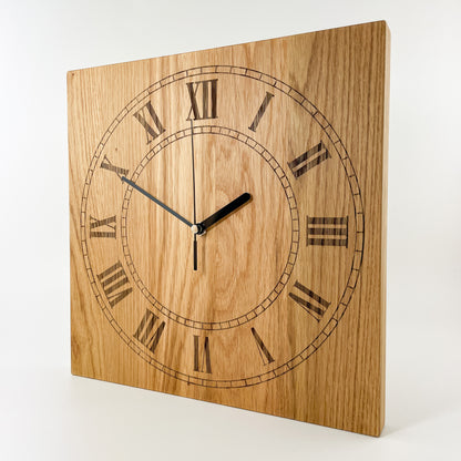 Perspektivansicht der quadratischen Eichenholz-Wanduhr Remus mit römischen Ziffern I bis XII und schwarzen schleichenden Zeigern vor heller Holzmaserung.